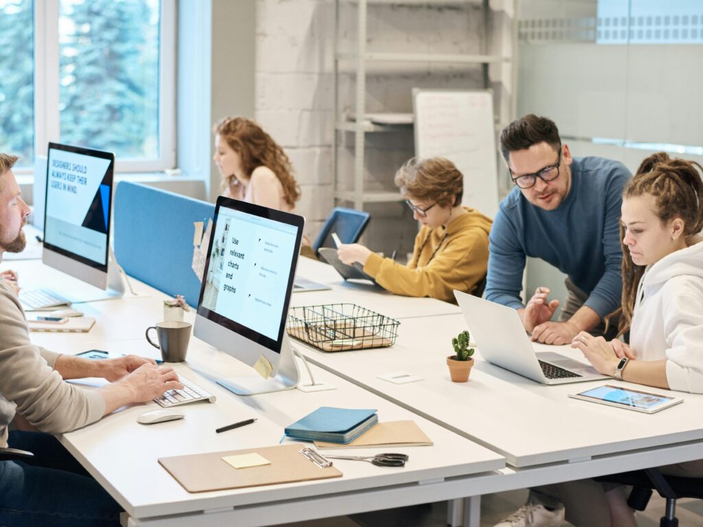 Team collaboration in a modern office setting with computers and diverse employees working together.